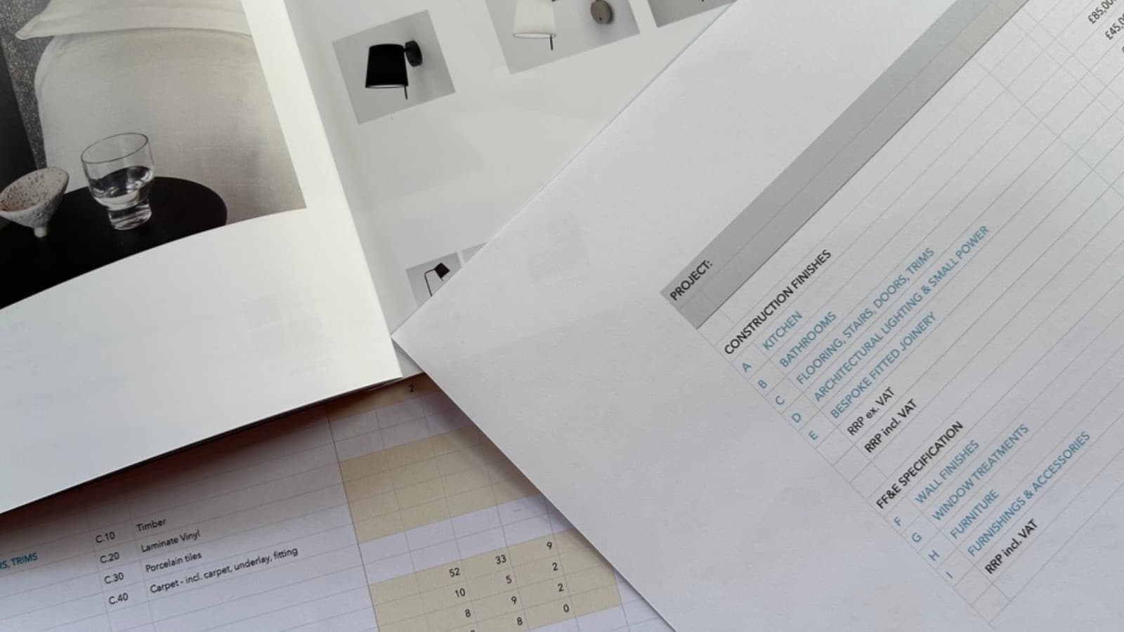 Printed drawings and schedules spread across a table.